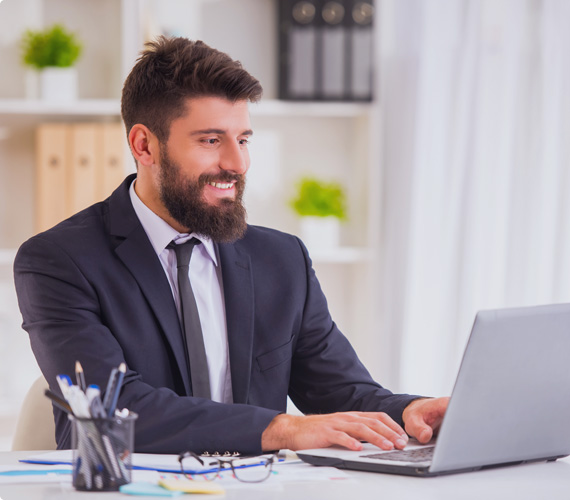 Imagem de homem sentado a mesa, digitando em notebook